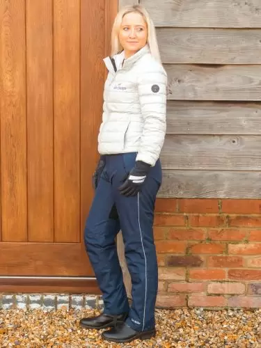 A horse rider standing by barn door wearing a pair of Dri-Rider waterproof riding trousers in navy by Just Chaps