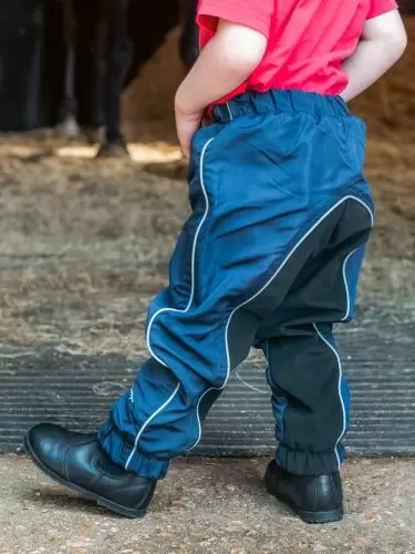 Toddler standing in stable door wearing a pair of kids Dri-Rider waterproof riding trousers in navy by Just Chaps