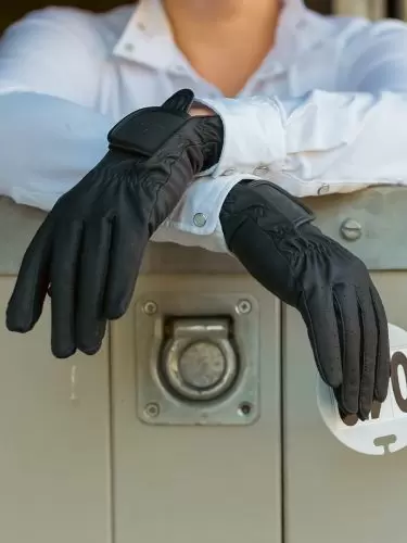 Horse rider standing by stable door wearing a pair of Competition gloves in black by Just Chaps