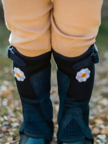 Toddler wearing a wearing a pair of black half chaps with daisy motif by Just Chaps