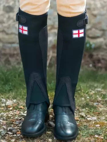 Front view of adult horse rider wearing a pair of half chaps in black neoprene with an England flag motif by Just Chaps