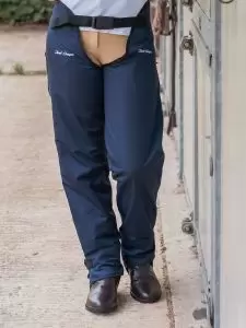 Rider standing by stable door wearing a pair of Adult Dri-Rider waterproof full chaps in navy by Just Chaps