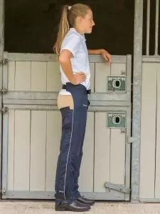 Child standing by stable door wearing a pair of kids Dri-Rider waterproof full chaps in navy by Just Chaps